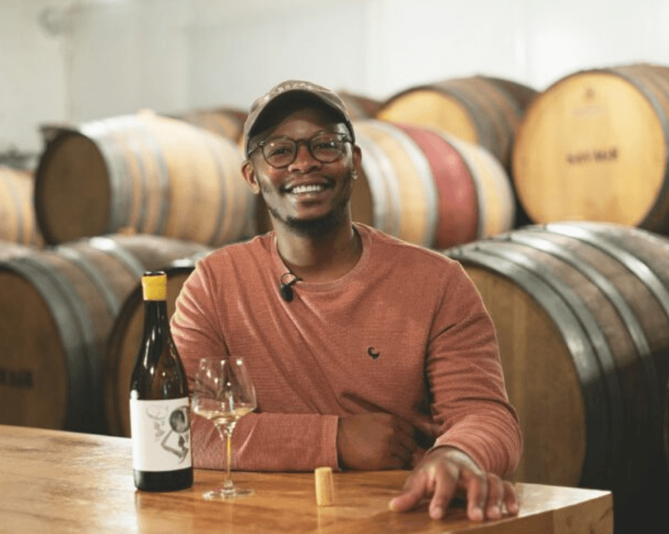 Banele Vakele, one of the contestants of the show, sitting down with a glass of wine and bottle in front