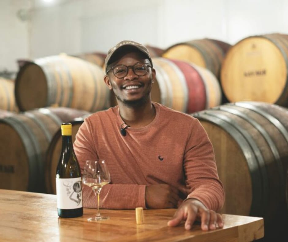 Banele Vakele, one of the contestants of the show, sitting down with a glass of wine and bottle in front